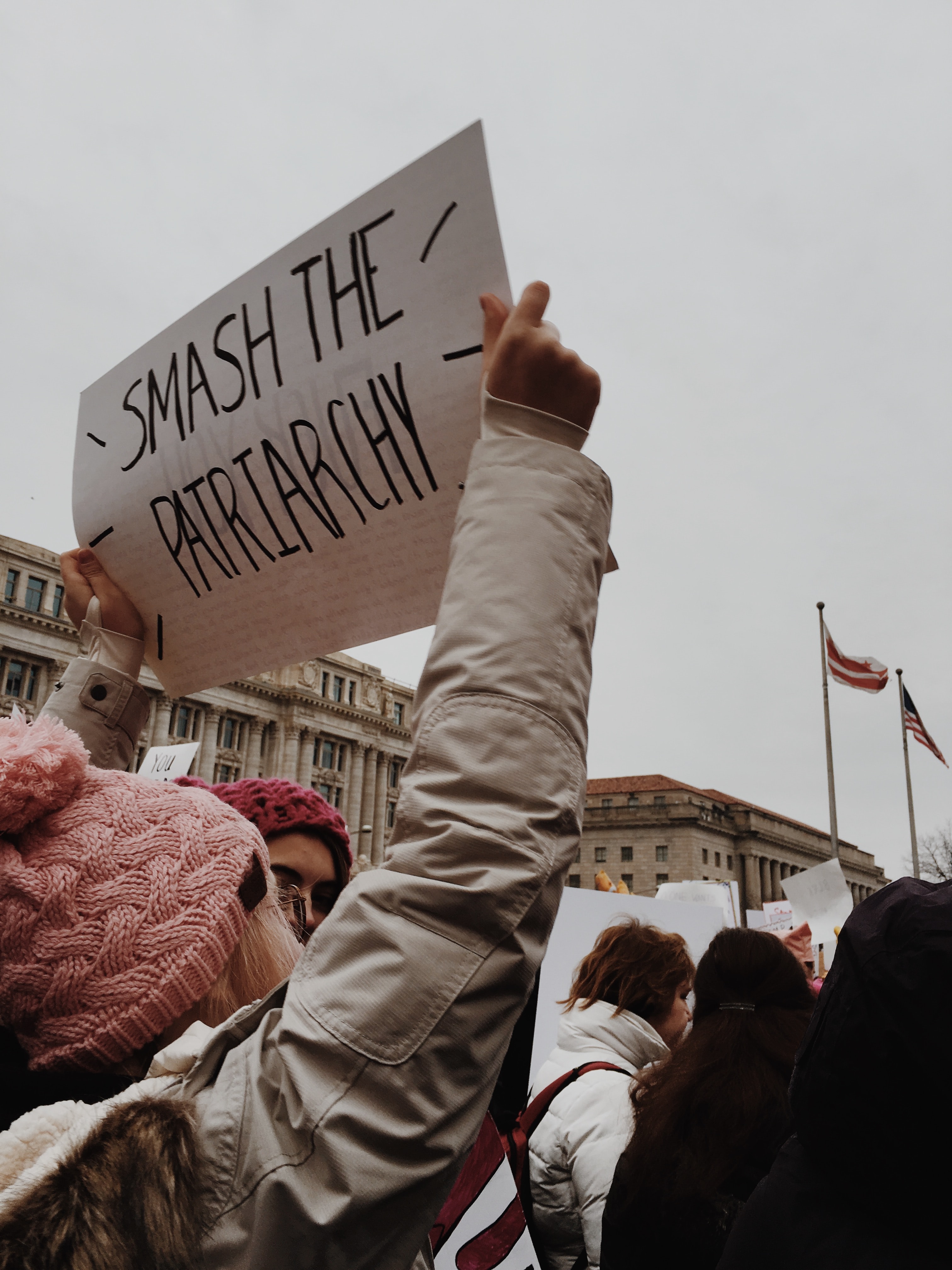 a person holding a sign reading 'smash the patriarchy'
