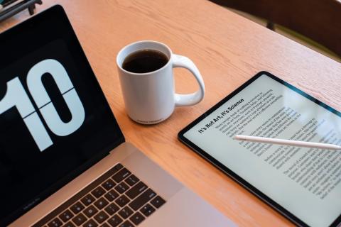 Open laptop next to mug of coffee and tablet showing eBook