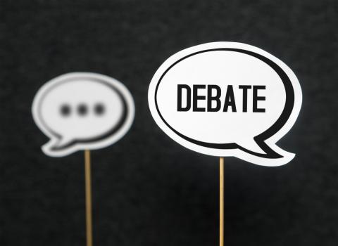 Two cartoon speech bubbles on a black background, with the nearer one saying "Debate" inside and the further with "..." inside.